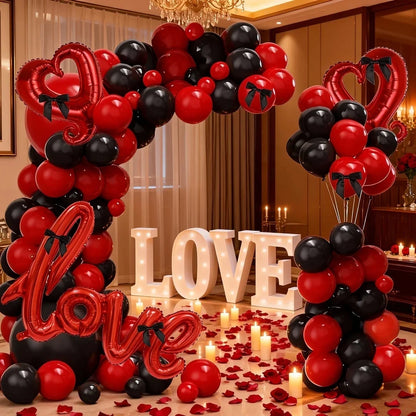 Decorative balloon arch with red, black, and white balloons, 'LOVE' letters, and candles in a room setting.