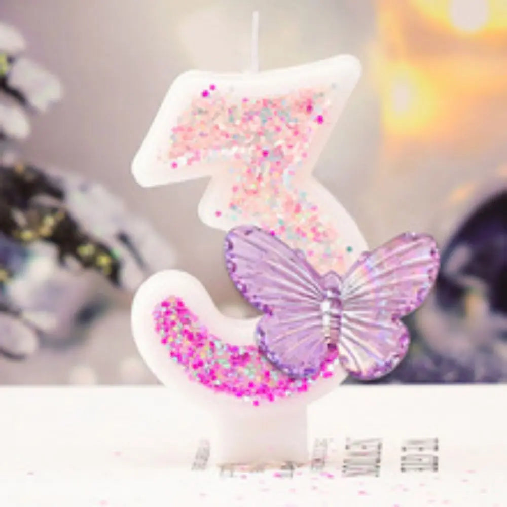 Decorative candle shaped like a number three with a butterfly and pink sprinkles on a blurred background.