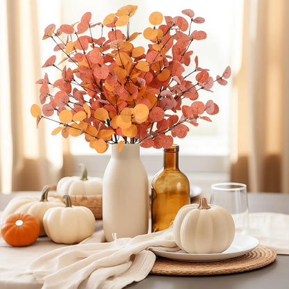 Autumn-themed table setting with pumpkins, leaves, and a vase.