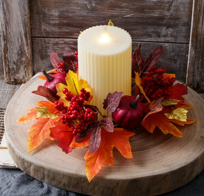 Decorative candle with autumn leaves and berries on a wooden surface