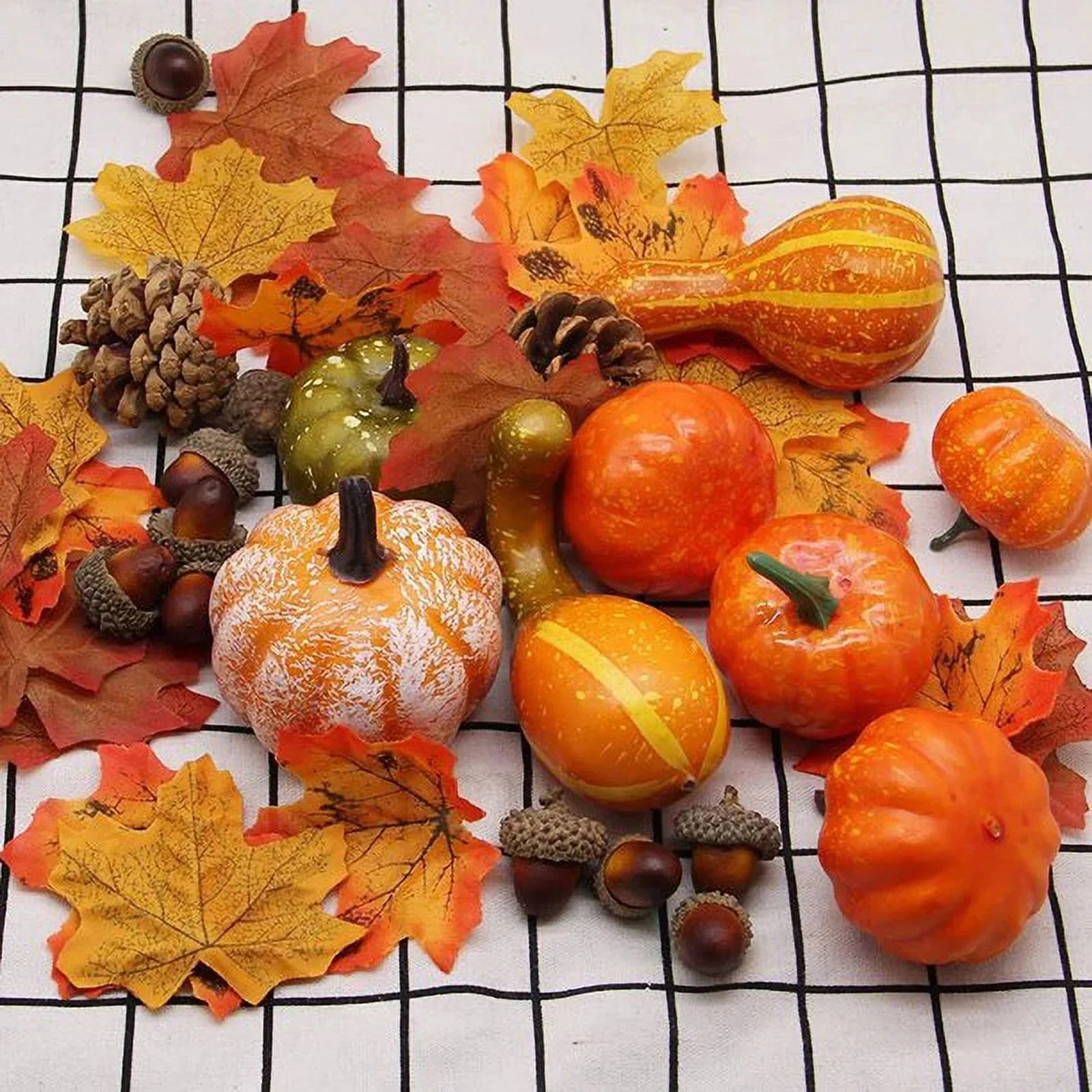 Decorative arrangement of pumpkins, gourds, and fall leaves on a checkered background
