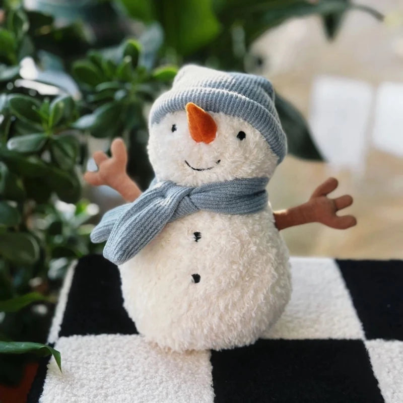 Plush snowman toy with a blue scarf and hat on a checkered surface.