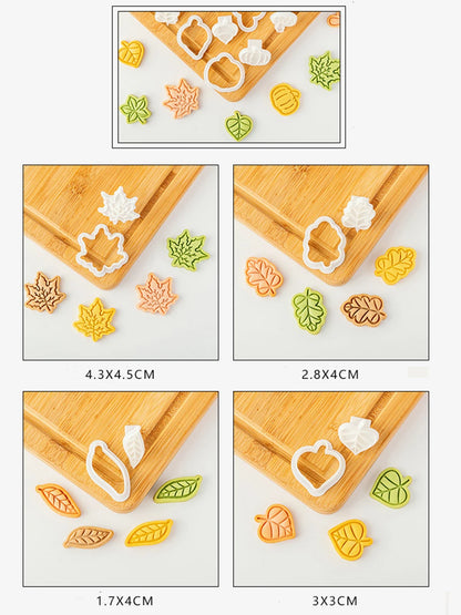 Set of colorful leaf-shaped cookie cutters on a wooden board with measurements.