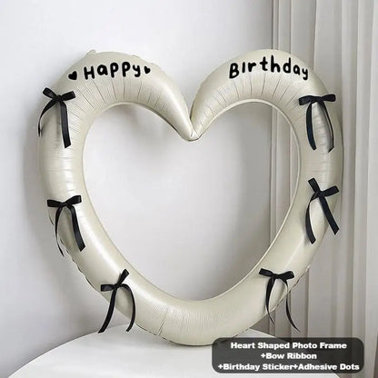 Heart-shaped photo frame with birthday stickers and ribbons on a white background