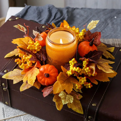 Decorative arrangement with a lit candle, pumpkins, and leaves on a suitcase.