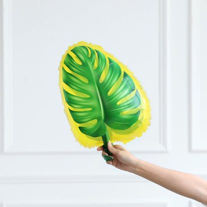 Hand holding a large green and yellow leaf-shaped object against a white background