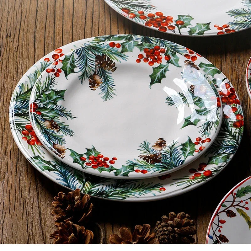 Set of Christmas-themed ceramic plates with holly design on a wooden surface.