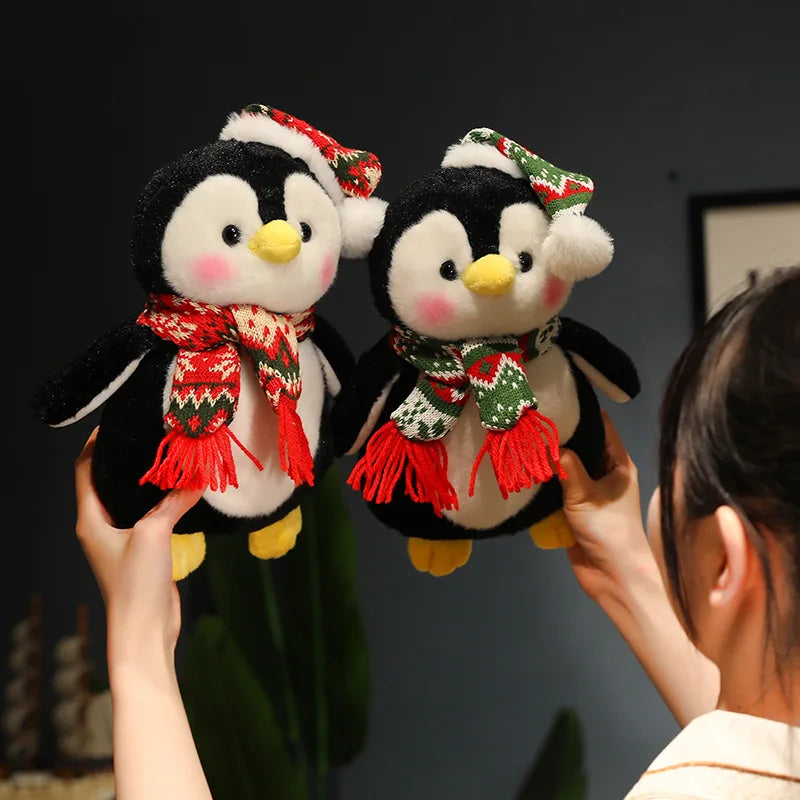 Two plush penguins with scarves and hats held by a person against a dark background