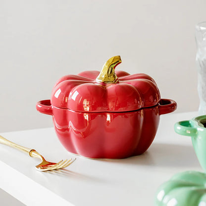 Red pumpkin-shaped cookware with a gold lid knob on a white surface.