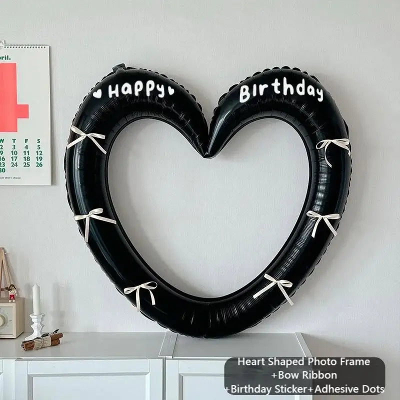 Heart-shaped photo frame with 'Happy Birthday' text on a white wall.