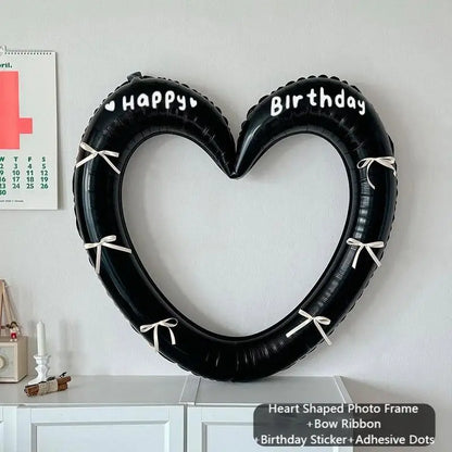 Heart-shaped photo frame with 'Happy Birthday' text on a white wall.