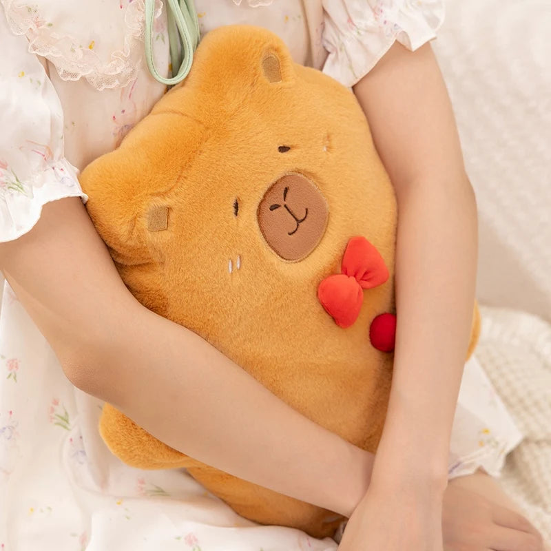 Person holding a plush capybara-shaped pillow with red bow accents.