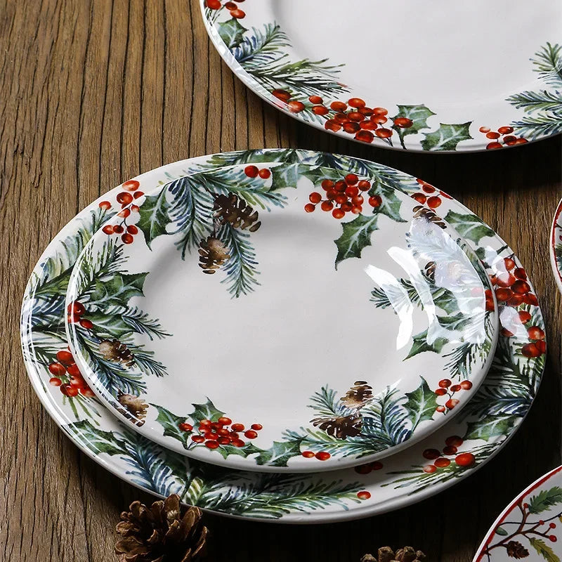 Set of Christmas-themed ceramic plates with holly design on a wooden surface.