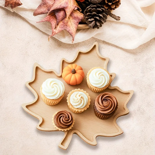Decorative leaf-shaped plate with cupcakes and a small pumpkin on a neutral background