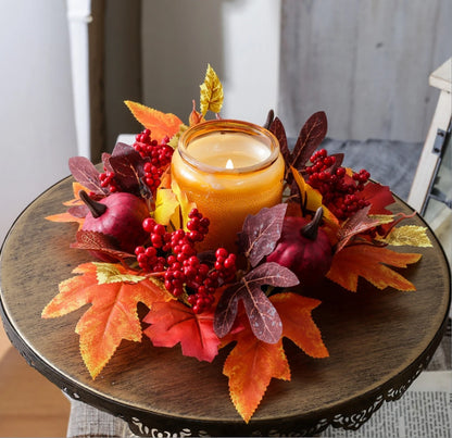 Decorative candle holder with autumn leaves and berries on a wooden table.