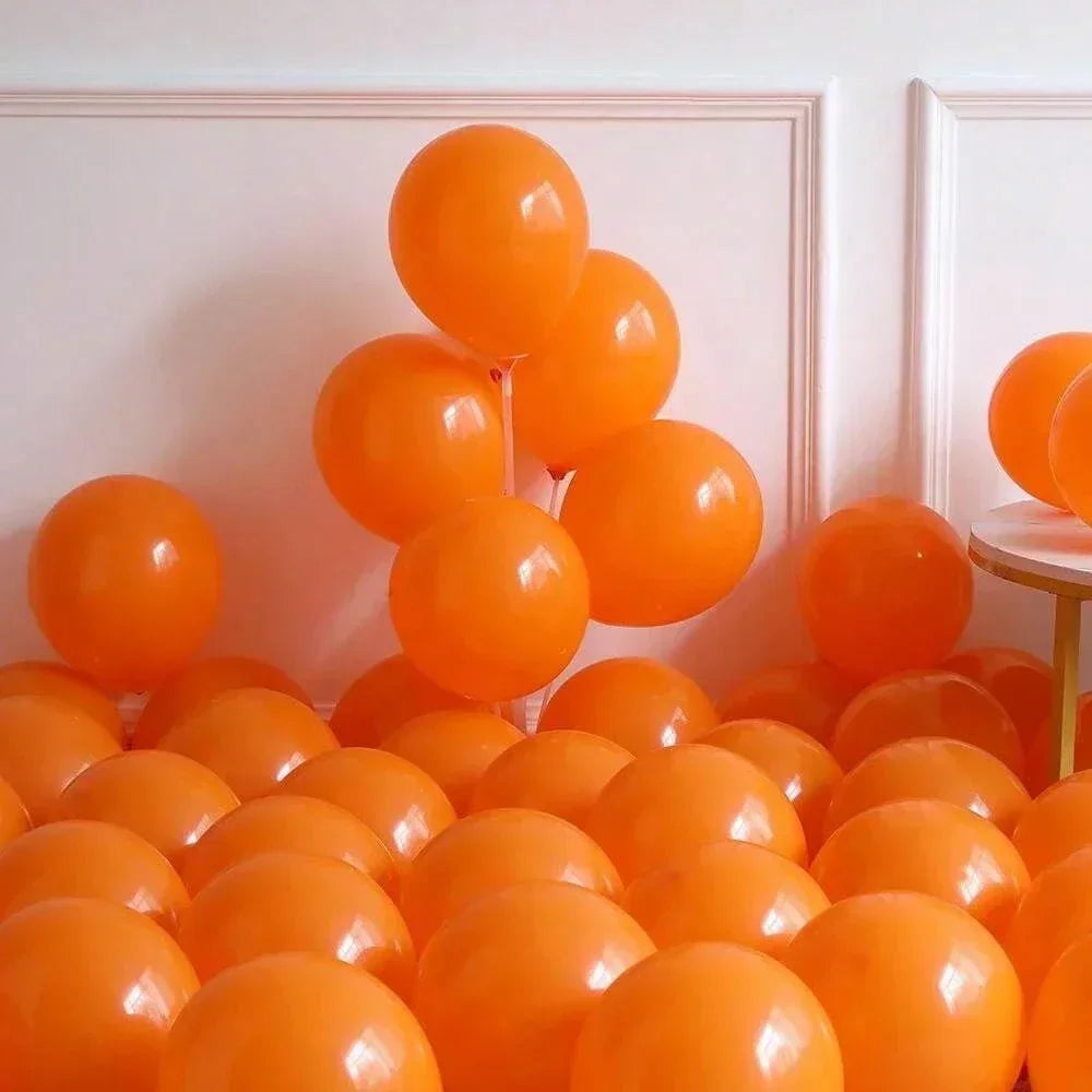 Orange balloons arranged in a decorative pattern against a white wall.