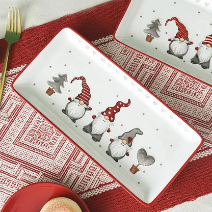 Decorative plate with Christmas-themed gnomes on a red and white patterned tablecloth.