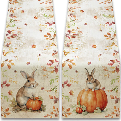 Two kitchen towels with autumn-themed designs featuring rabbits and pumpkins.