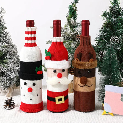Three wine bottles wrapped in festive knitted covers with Christmas-themed designs against a white background.