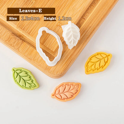 Leaf-shaped cookie cutters on a wooden board with measurements displayed.