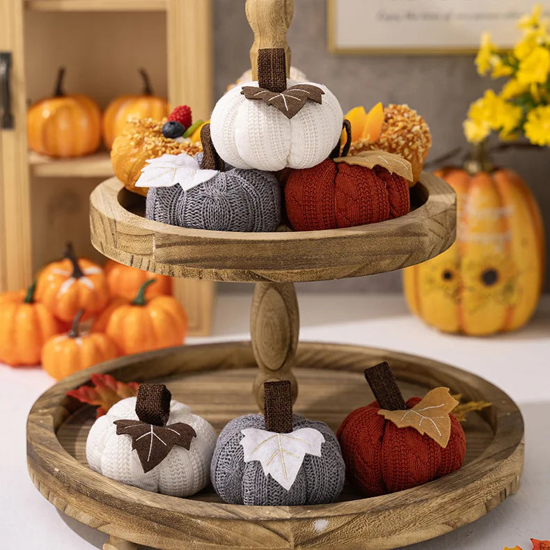 Wooden tiered stand with decorative pumpkins on a table with pumpkins in the background.