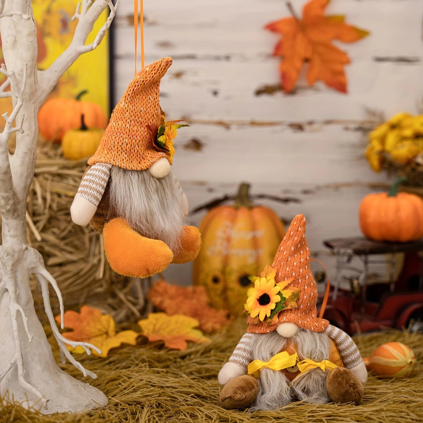 Two autumn-themed gnomes with pumpkins and leaves in a decorative setting.