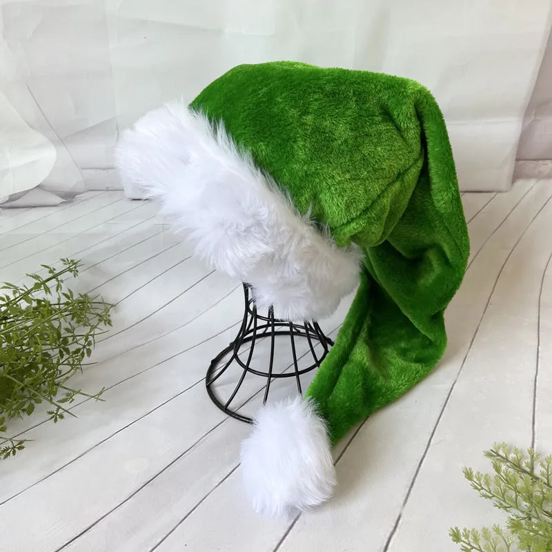Green Santa hat with white fur trim on a wooden floor.
