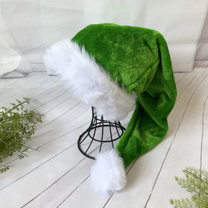 Green Santa hat with white fur trim on a wooden floor.