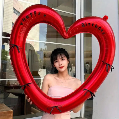 Woman holding a large red heart-shaped balloon with 'Happy Birthday' text.