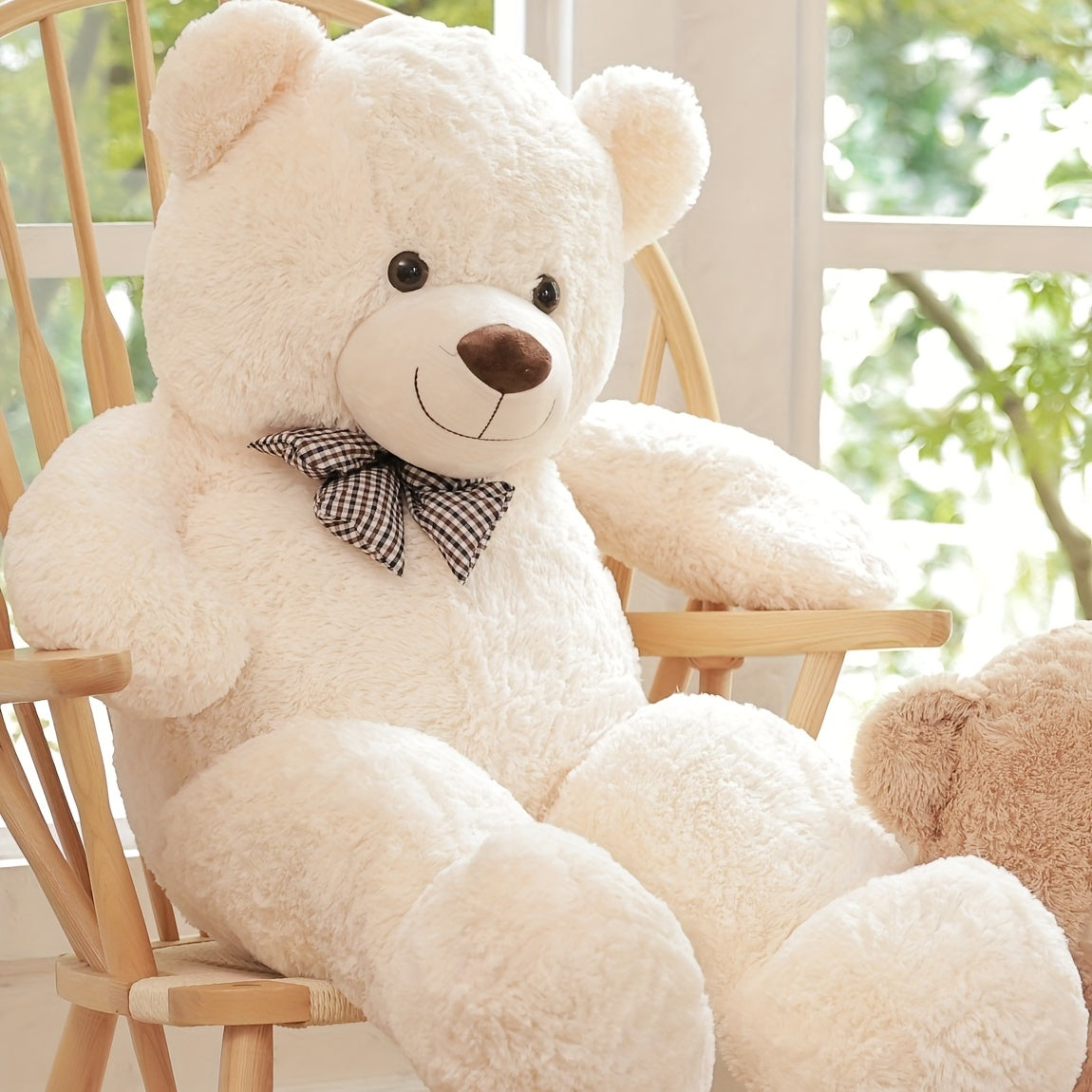 Large beige teddy bear with a bow tie sitting on a wooden chair.