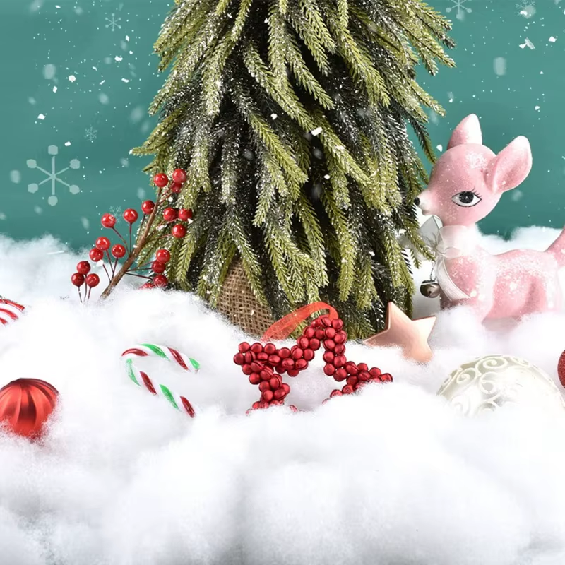 Christmas scene with a decorated tree, ornaments, and a pink deer figurine on snow.
