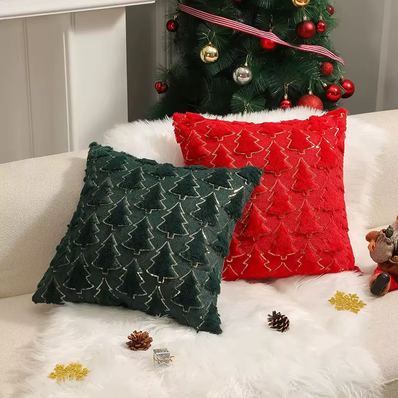 Two Christmas-themed pillows, one green and one red, on a white couch with a decorated Christmas tree in the background.