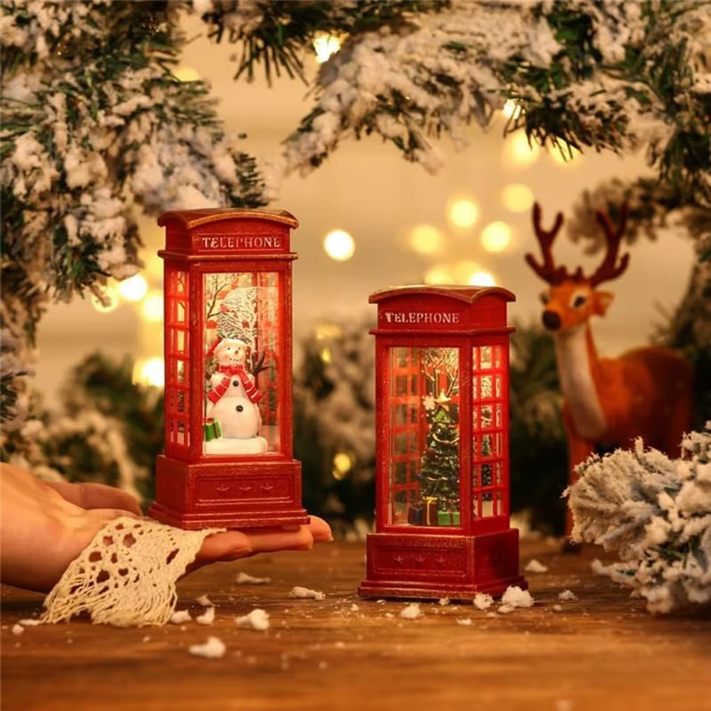 Two miniature red telephone booths with Christmas decorations against a festive background with lights and a deer.