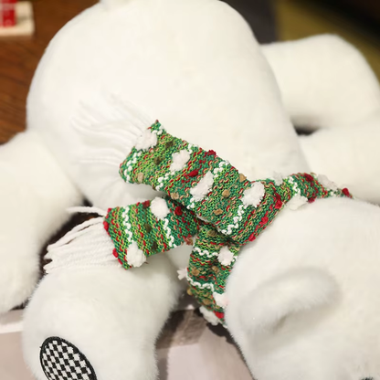 White teddy polar bear with green and red knitted scarf on a blurred background